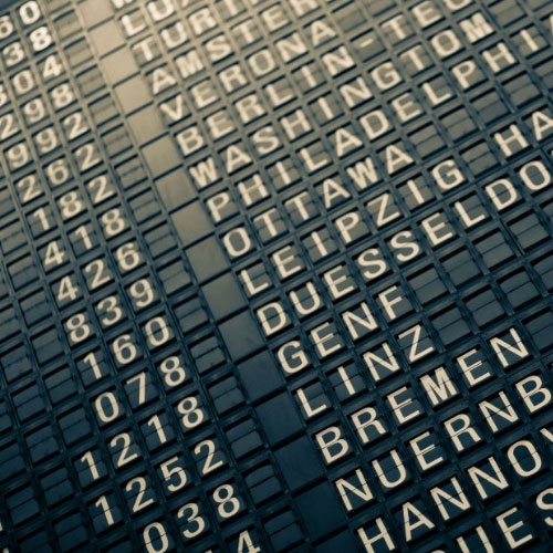 A close-up of an airport departure board with associated airport codes