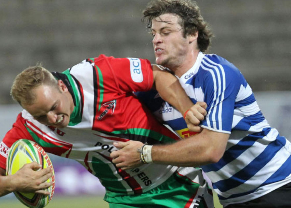  Photo of a rugby player in red being tackled by a player in blue 